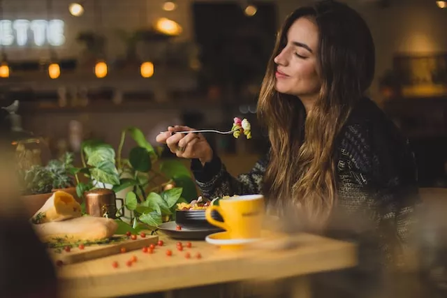 A woman holding a fork in a restaurant, enjoying her food and being happy.